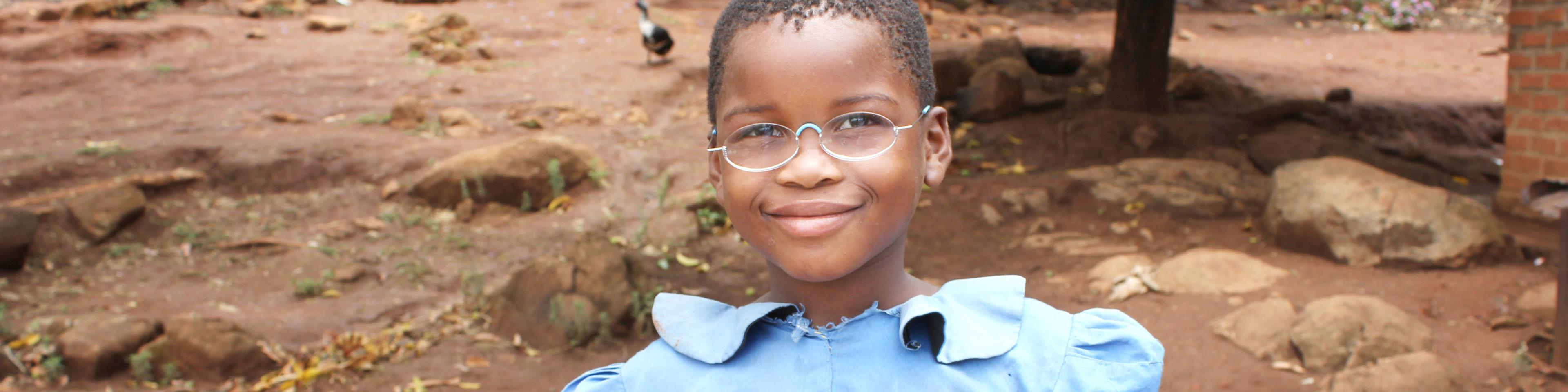 Schülerin aus Malawi, mit Schulheft und Stift, trägt EinDollarBrille